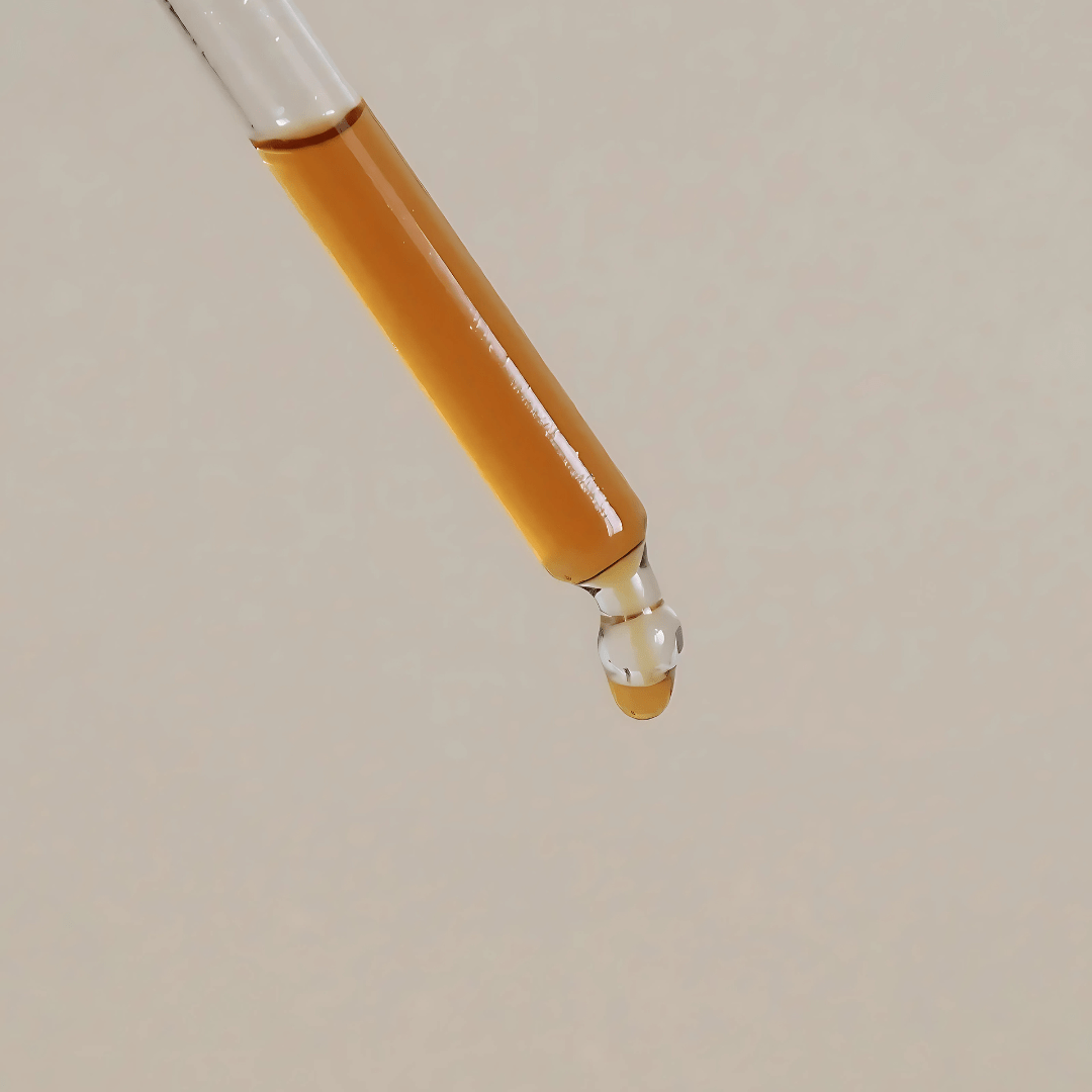 Orange colored serum drop of product about to drip.