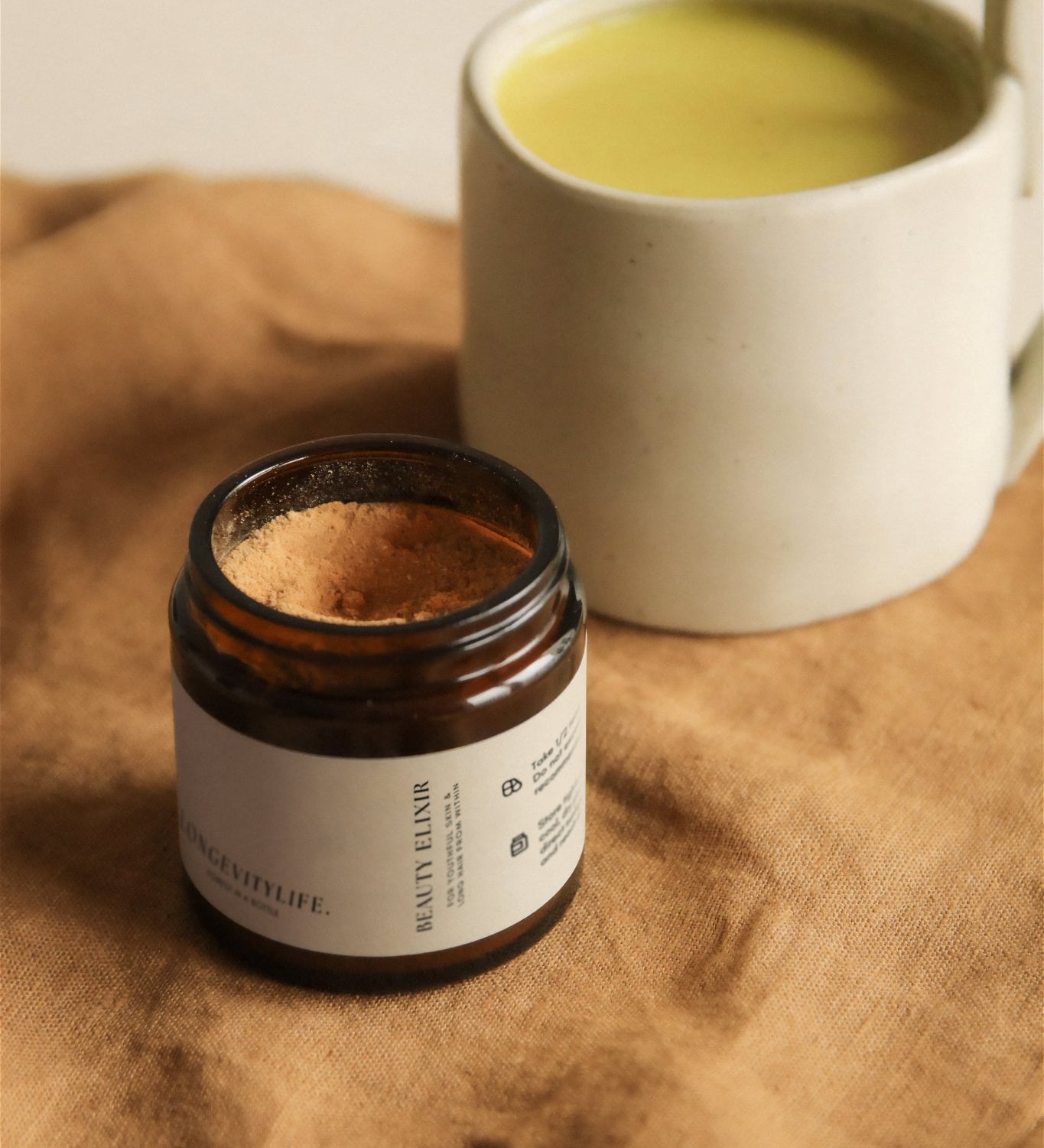 Beauty Elixir powder with golden latte on fabric.