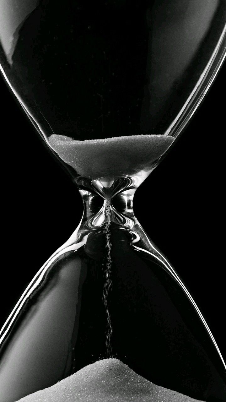 An hourglass with sand flowing from the top chamber to the bottom, indicating the passage of time.