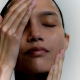 A woman, cleaning her face with her hands.