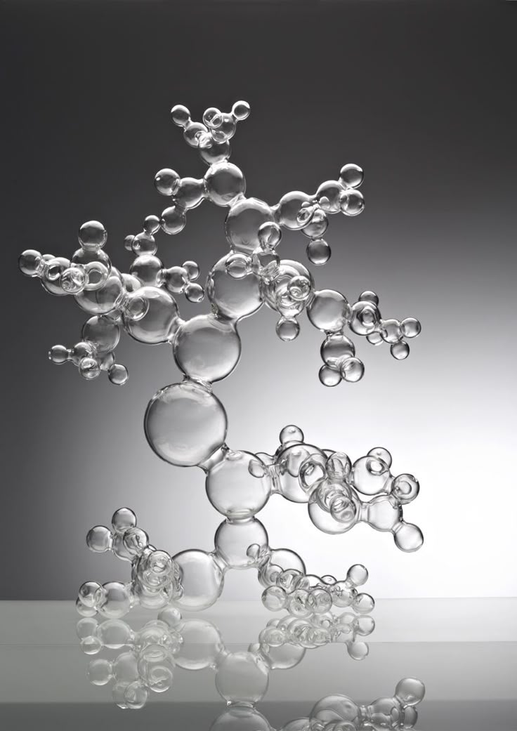 An artistic glass sculpture of bubbles rests on a table, reflecting light beautifully.