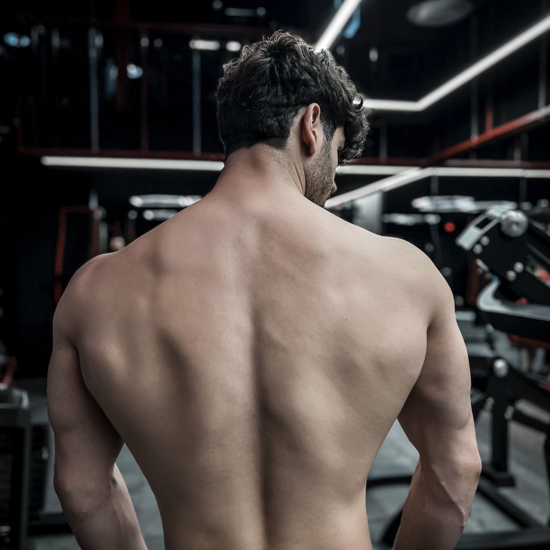 Mann mit nacktem Oberkörper von hinten im dunklen Gym, Thema Nasenstrips vor dem Training