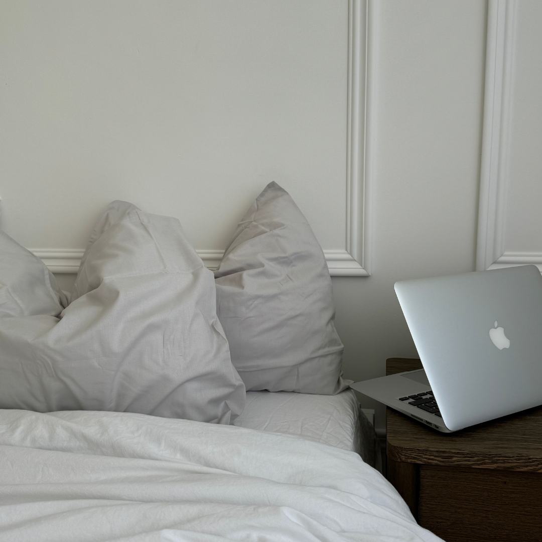 Bett mit hellgrauer Bettwäsche und Laptop auf dem Nachttisch, Thema Nasenstrips mit Duft am Abend