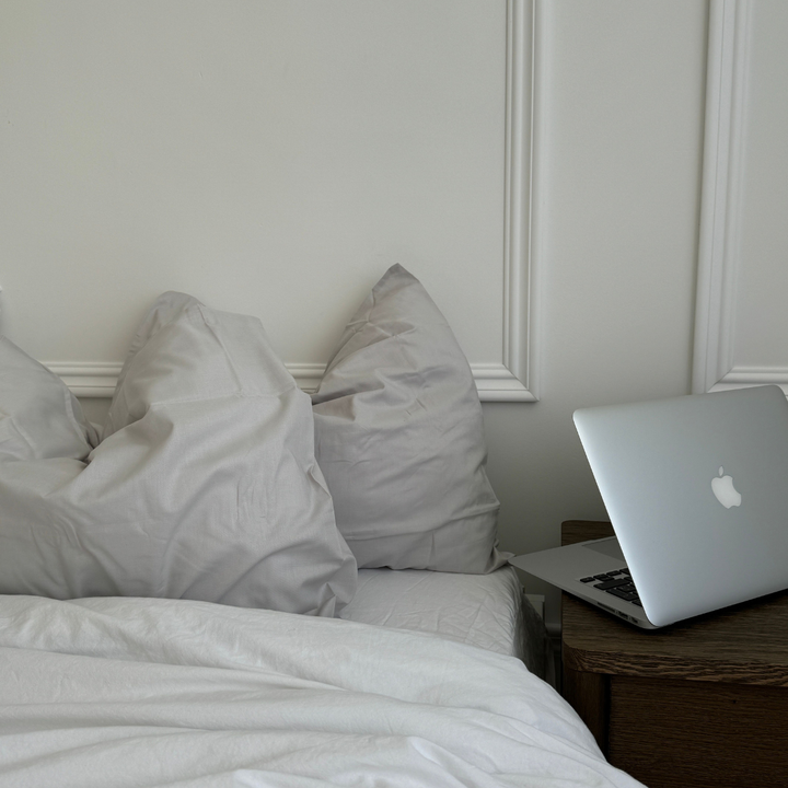 Bett mit hellgrauer Bettwäsche und Laptop auf dem Nachttisch, Thema Nasenstrips mit Duft am Abend