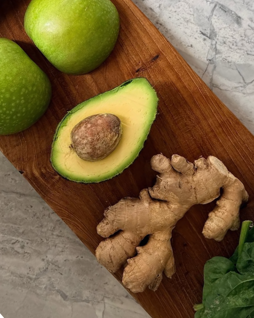 Halbierte Avocado, grüne Äpfel, Ingwer und Spinat auf einem Holzbrett, gesunde Lebensmittel für jeden Tag