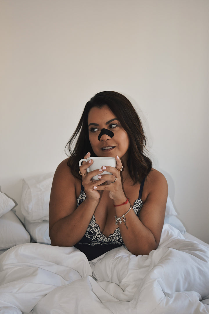 Frau im Bett mit LongevityLife Nasenstrip und Tasse, Longevity Produkte für die Abendroutine