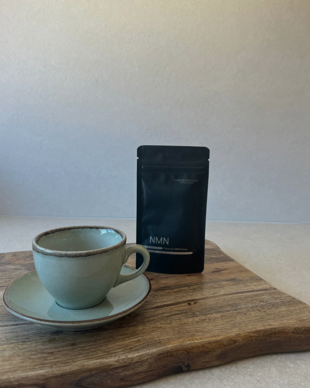Tasse auf einem Holzbrett neben dem LongevityLife NMN Beutel, ruhige Longevity Routine am Morgen