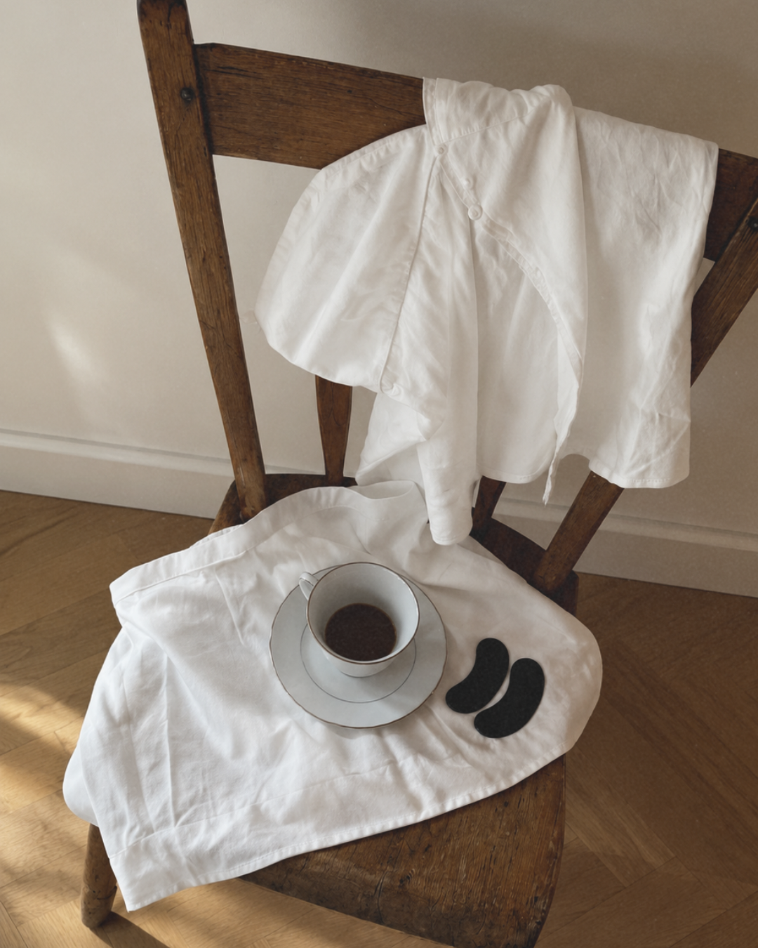 Holzstuhl mit weißem Leinen, Tasse und zwei schwarzen LongevityLife Nasenstrips für die Abendroutine