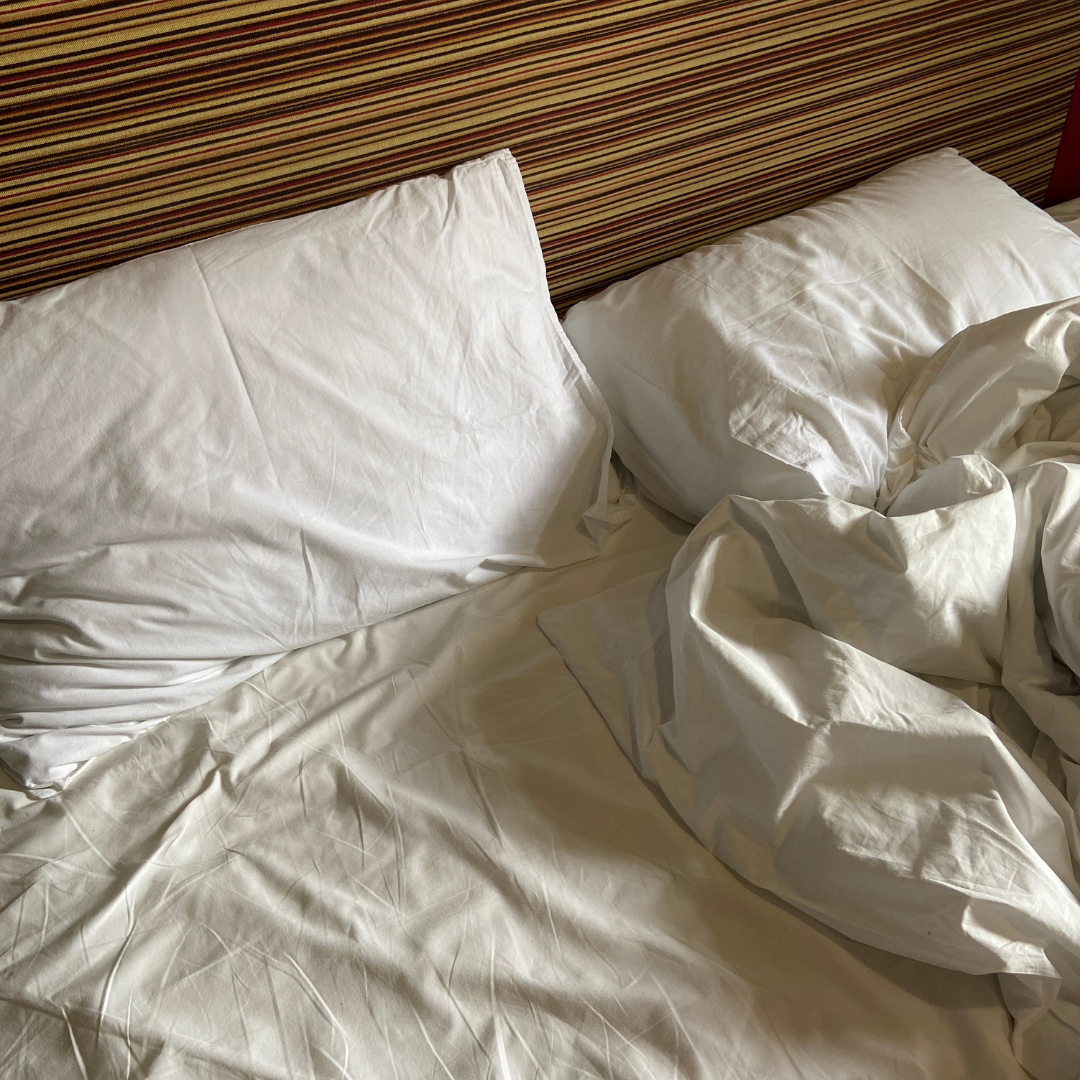 Ungemachtes Bett mit weißer Bettwäsche und zerwühlter Decke, Sinnbild für die Nacht mit Nasenstrips