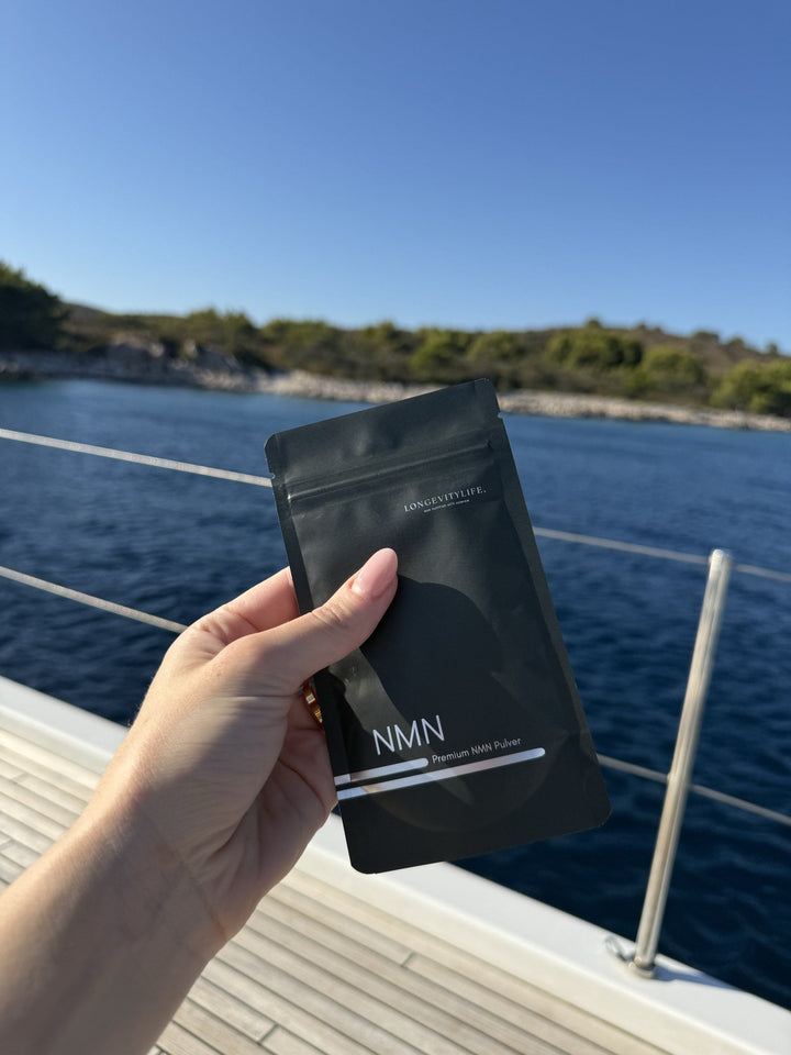 Hand hält NMN Pulver von LongevityLife auf einem Boot vor dem Meer
