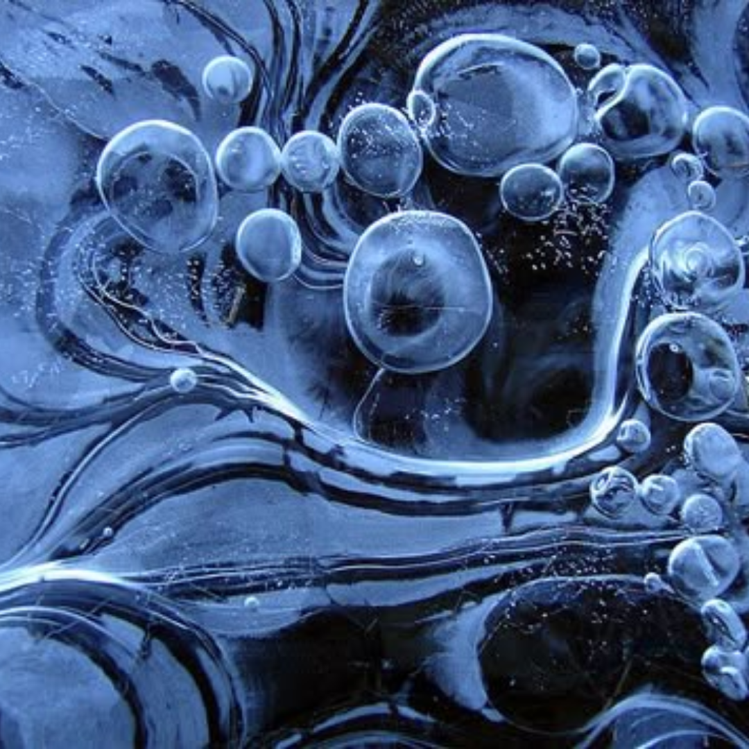 Close-up of bubbles in a fluid, possibly oil and water, with a dark background.