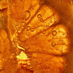 Close-up of orange juice containing air bubbles.