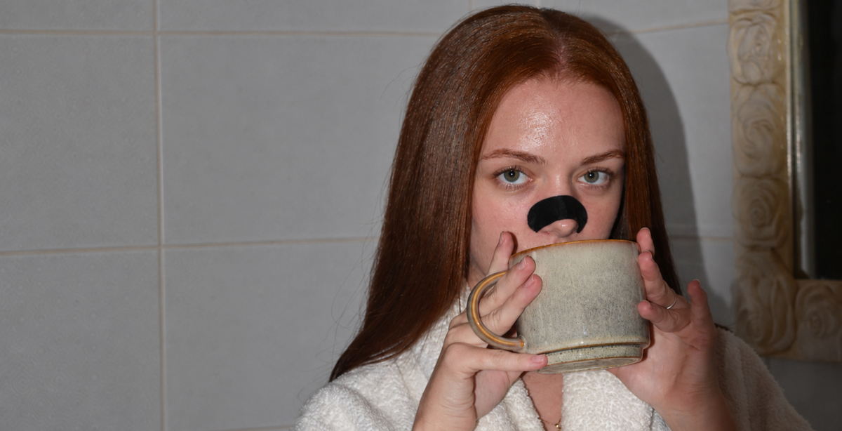 Woman with a silk nasal strip drinking from a mug in the bathroom