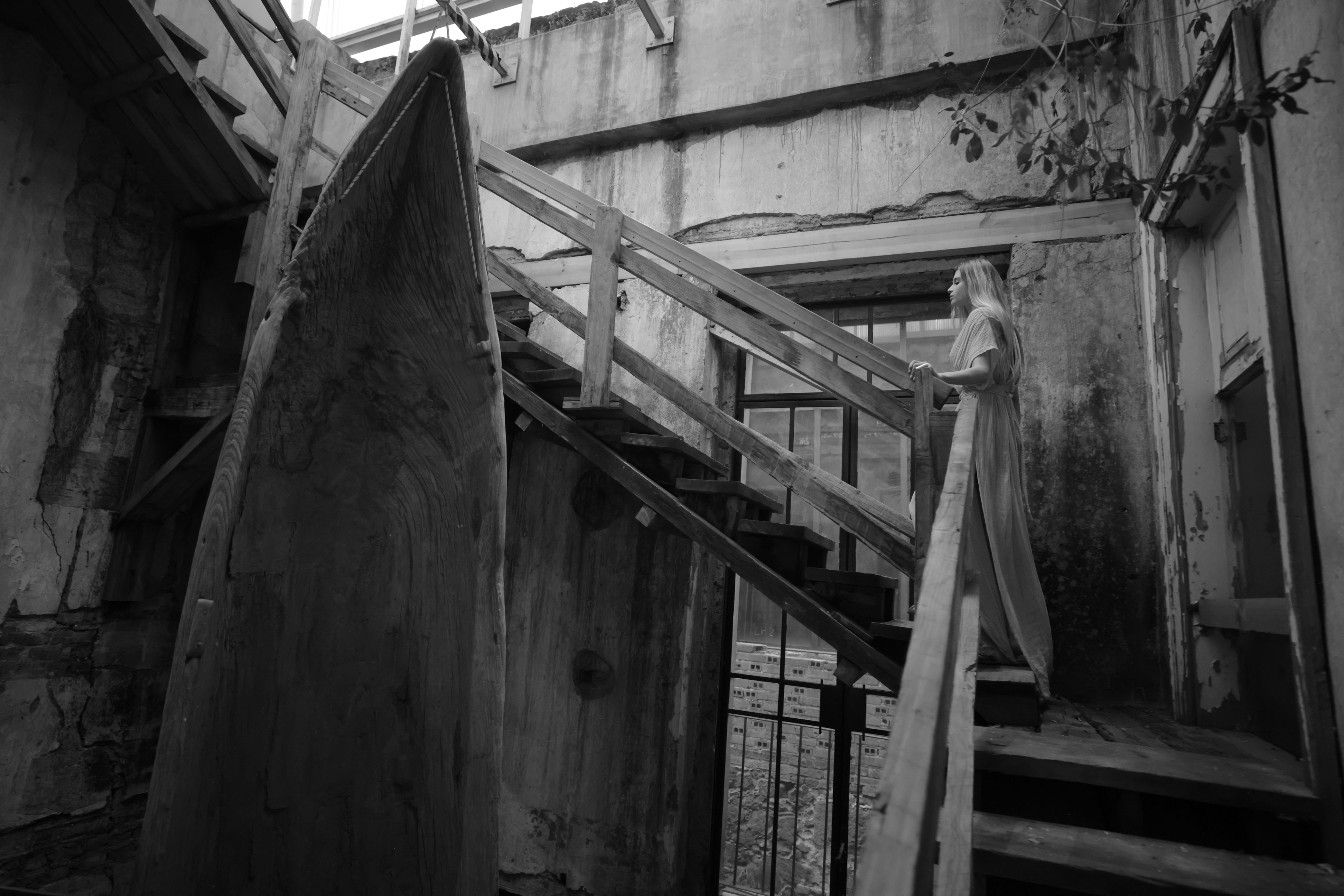 A black and white image depicting a staircase in an aged building, highlighting its historical design and texture.