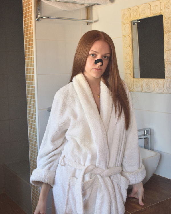 Frau im weißen Bademantel mit LongevityLife Nasenstrip im Badezimmer