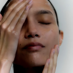 A woman, cleaning her face with her hands.