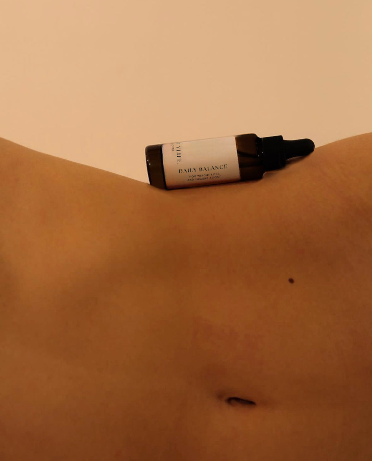 A woman's abdomen with a bottle of Daily Balance resting on it, emphasizing a connection to health or beauty routines.