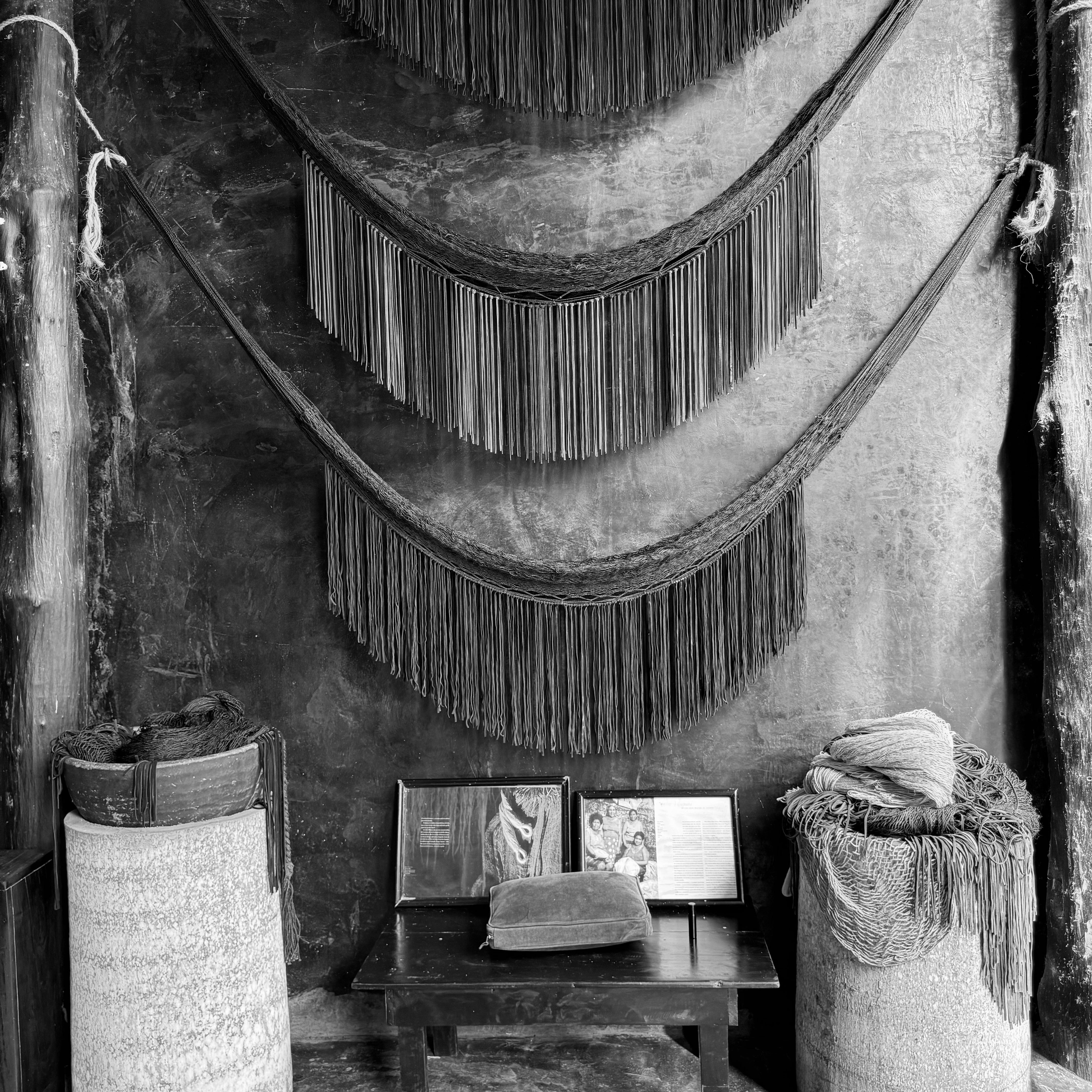 A black and white photo of a room featuring woven baskets and a wall adorned with decorative tassels.