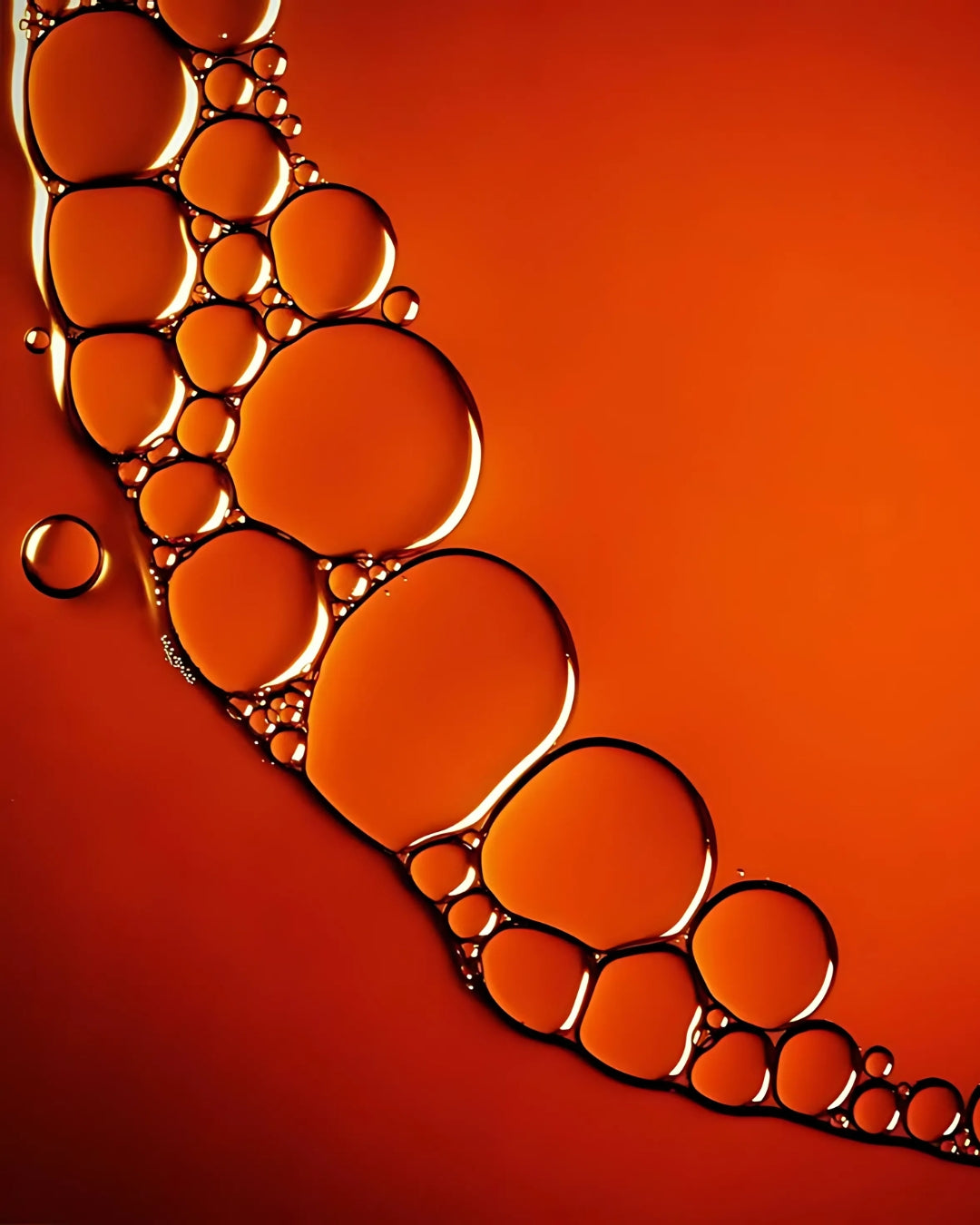 A collection of oil bubbles rests on a bold red background.