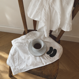 Tasse Kaffee und zwei Silk-Nasenpflaster auf einem Holzstuhl mit weißem Leinen