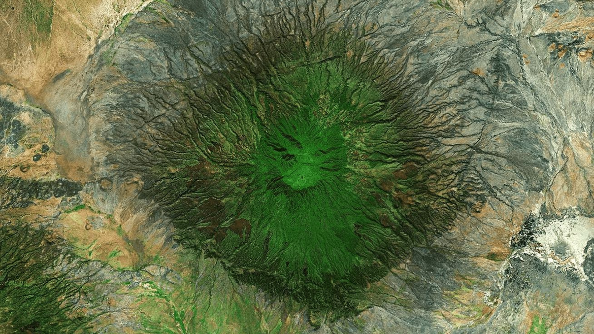 Aerial view of a volcano covered in green grass, showcasing the natural landscape from above.