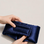 Hände zeigen die gesteppte Rückseite der Satin-Schlafmaske in Night Blue