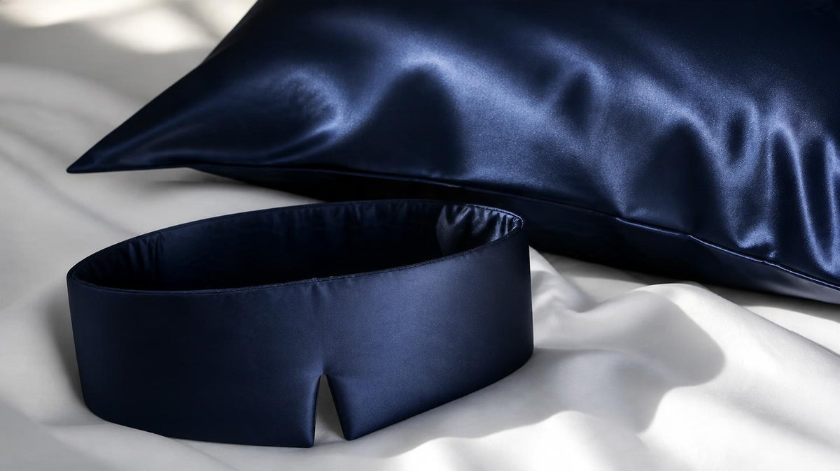 Satin-Schlafmaske und Satin-Kissenbezug in Night Blue mit sanftem Glanz auf weißer Bettwäsche